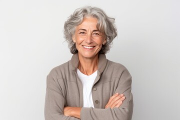 Wall Mural - Headshot portrait photography of a grinning mature woman making a i'm cold gesture by hugging oneself against a white background. With generative AI technology