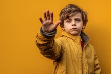 Photography In The Style Of Pensive Portraiture Of A Glad Boy In His 30s Making A No Or Stop Gesture With The Extended Palm Against A Mustard Yellow Background. With Generative AI Technology