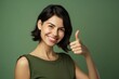 © Markus Schröder - Headshot portrait photography of a glad girl in her 30s raising both thumbs up against a pastel green background. With generative AI technology