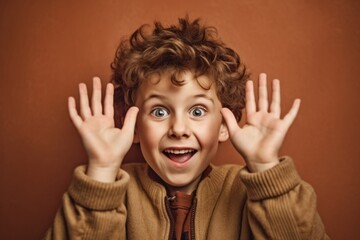 Wall Mural - Close-up portrait photography of a happy boy in his 30s making a sorry gesture with hands together against a warm taupe background. With generative AI technology