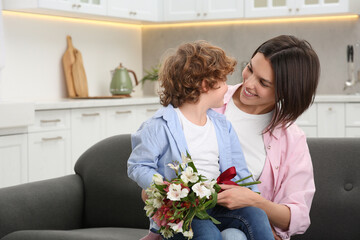 Canvas Print - Happy woman with her cute son and bouquet of beautiful flowers at home. Mother's day celebration