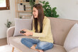 © Pichsakul - Concept of activity in home, Young woman sit on couch to playing video game with joystick console