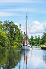 Sticker - Canal with an old sailboat in a summer landscape