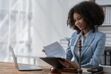 American woman lawyer or businesswoman African working with laptop searching for information, reading codes, documents, studying constitution to protect rights work with law books hammer of justice.