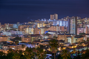 City, buildings and urban landscape at night, skyline and location with architecture, landmark and travel. Cityscape, skyscraper and Cape Town view for tourism, traveling and background destination