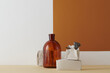 © TrueFrame Collective - Horizontal shot of contemporary color-blocking still life composition with brown glass vessel, dried lotus and gypsum bricks against white and terracotta wall background, copy space