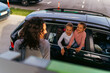 © DusanJelicic - a mother looks over her shoulder at her children who are in the car as she fills up the fuel tank