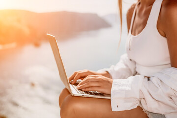 Woman sea laptop. Business woman in yellow hat freelancer with laptop working over blue sea beach. Girl relieves stress from work. Freelance, digital nomad, travel and holidays concept