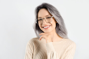 Portrait of smiling woman with ash hair color on light background