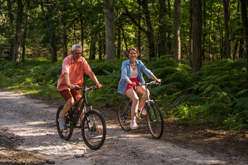 Senior man and his daughter riding bicycles in summer forest