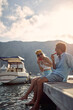 © luckybusiness - Eating watermelon. Couple enjoying summertime holiday. Sitting on wooden jetty by water. Boats in background. Love, holiday, lifestyle concept.