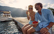 © luckybusiness - Couple laughing and eating watermelon. Sitting by water on wooden jetty. Couple in love. Tourism, summertime, togetherness, lifestyle concept.