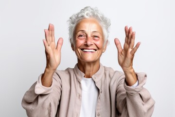 Wall Mural - Medium shot portrait photography of a grinning mature woman joining palms in a gesture of gratitude against a white background. With generative AI technology