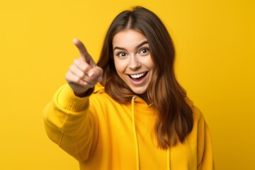Wall Mural - Headshot portrait photography of a joyful girl in her 20s pointing at oneself against a bright yellow background. With generative AI technology