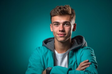 Canvas Print - Headshot portrait photography of a glad boy in his 20s crossing the arms against a teal blue background. With generative AI technology