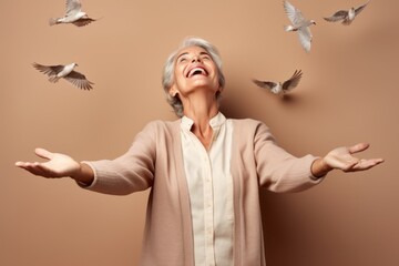 Canvas Print - Medium shot portrait photography of a satisfied mature woman imitating the flight of a bird with the hands against a beige background. With generative AI technology