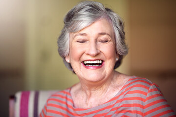 Happy, senior woman and eyes closed in nursing home, living room or laughing in house or relax in retirement. Elderly lady, happiness and smile or laugh at funny, joke with freedom of retired person