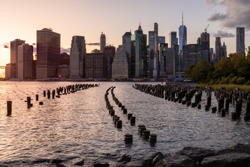 Poster - Beautiful Sunset and Lower Manhattan skyline with East River and New York City. Twilight with Reflections and Abandoned Pier at Sunset from Brooklyn Bridge Park