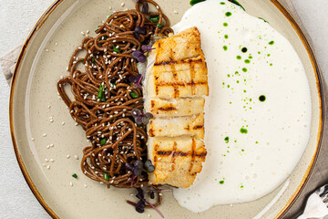Wall Mural - Portion of halibut fillet with soba noodles and creamy sauce