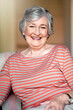 Home, happy and portrait of a senior woman with a smile for retirement and old people happiness. Relax, lounge and an elderly lady in a chair in the living room with confidence and comfort in morning