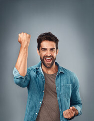 Wall Mural - Happy man, fist and celebration for winning, success or victory against a grey studio background. Excited portrait of male person or winner in achievement, win or accomplishment on mockup space