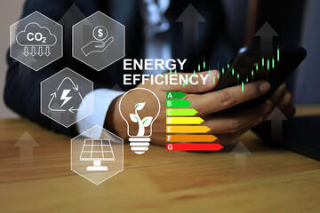 A man using smartphone to choose  an electric light bulb with tree inside and an energy saving rating sign to tell customer the value of the product to make a decision. Energy saving and zero co2