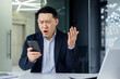 © Liubomir - Confused Asian guy holding smart phone feels concerned thinking over received message. Mobile phone everyday usage, unpleasant news, waiting for important call, low signal device problems concept