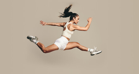 active female athlete running mid air in a vigorous trining session