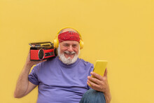 Cheerful senior man using smartphone and listening to music