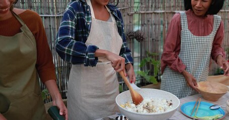 Wall Mural - Asian family cooking together traditional thai rice at home outdoor - Mother and two daughters having fun preparing dinner at house backyard