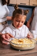 © dvulikaia - Little girl helps her mother to cook sweet cheesecake.