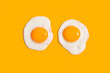 Two fried sunny-side-up eggs with bright glossy yoke on yellow background. Culinary food concept. AI generated