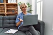© Krakenimages.com - Young man working using computer laptop sitting on the sofa celebrating achievement with happy smile and winner expression with raised hand
