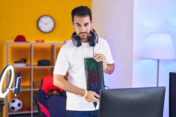 Poster - Young hispanic man streamer smiling confident holding keyboard computer at gaming room