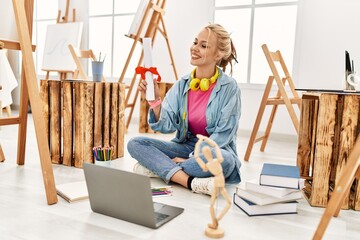 Wall Mural - Young caucasian woman artist holding diploma sitting on floor at art studio