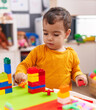 © Krakenimages.com - Adorable hispanic boy playing with construction blocks standing at kindergarten