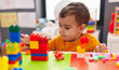 © Krakenimages.com - Adorable hispanic boy playing with construction blocks sitting on table at kindergarten