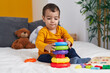 © Krakenimages.com - Adorable hispanic boy playing with hoops game sitting on bed at bedroom