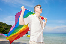 Young Man Holding A Rainbow Flag(LGBT) On A Tropical Beach