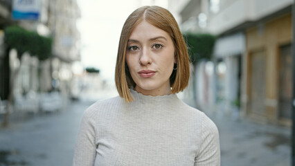 Poster - Young blonde woman standing with serious expression at street