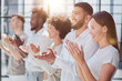 © Katsiaryna - Group of businesspeople sitting in a line and applauding.