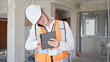 © Krakenimages.com - Young caucasian man architect talking on smartphone using touchpad at construction site