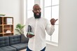 © Krakenimages.com - African american man working at therapy office using smartphone pointing thumb up to the side smiling happy with open mouth
