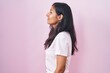 © Krakenimages.com - Young hispanic woman standing over pink background looking to side, relax profile pose with natural face and confident smile.