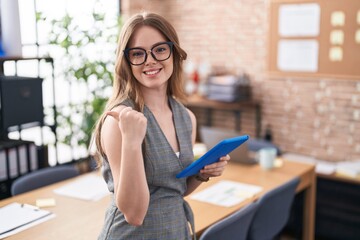 Poster - Caucasian woman working at the office wearing glasses pointing to the back behind with hand and thumbs up, smiling confident