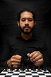 © Narayan - latin man with beard playing chess making decisions, chess concept