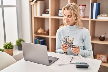 Sticker - Young blonde woman counting dollars sitting on table at home