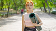 © Krakenimages.com - Young redhead woman wearing sportswear holding yoga mat at park