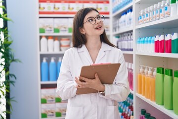 Wall Mural - Young caucasian woman pharmacist writing on document at pharmacy