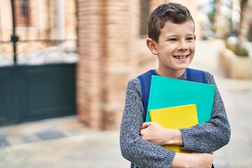 Wall Mural - Blond child student holding books standing at street